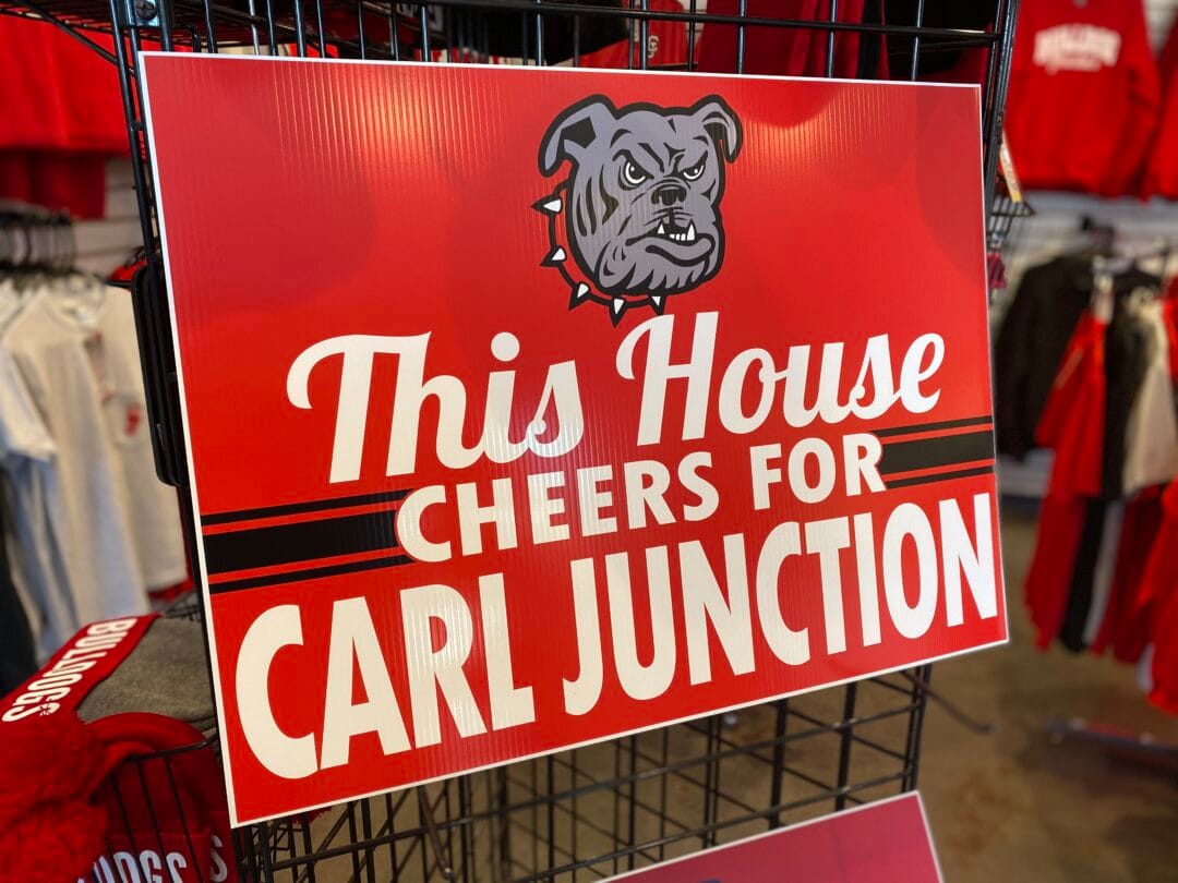 A Yard sign that says "This House Cheers for Carl Junction" with A buldogg on it.
