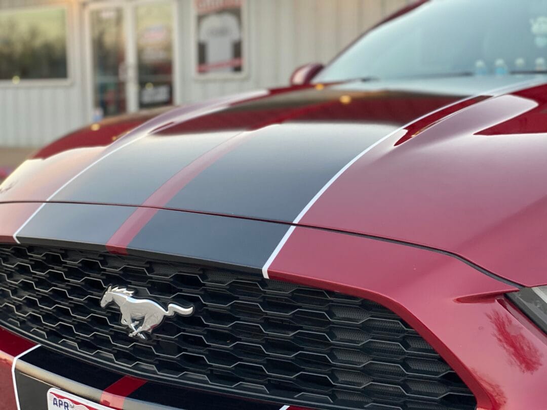 Custom vinyl racing stripes on the hood of a red Ford mustang done by Cutting Loose Graphics in Joplin, MO.